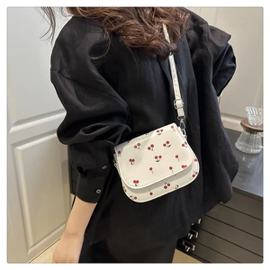 Close-up of cherry print saddle bag with adjustable strap on model back view