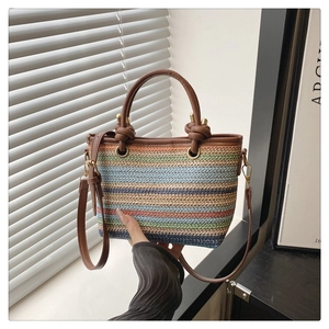 Détail du sac seau en paille arc-en-ciel avec poignées en cuir marron et nœuds