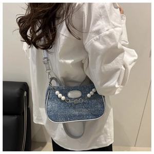 Close-up of blue denim small square bag with pearl chain and adjustable shoulder strap