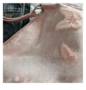 Detail einer rosa Jacquard-Tragetasche mit 3D-Schmetterlingsstickerei und Lederriemen