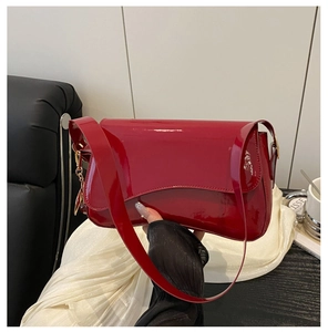 Detail of glossy red patent leather underarm bag with mirror-like finish and metal accents