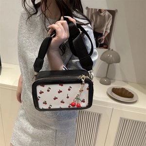 Chic black crossbody camera bag with red cherry prints and a cute cherry charm detail