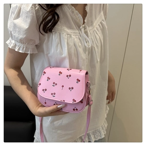 Detail of pink cherry print crossbody bag worn by model with white lace top