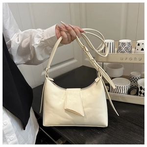 Detail of a creamy white leather underarm bag with gold hardware and adjustable strap