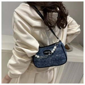 Detail of vintage denim shoulder bag with pearl chain and fashion leather patch