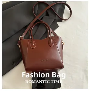 Detail of dark brown leather bucket bag with FASHION embossing and gold-tone hardware