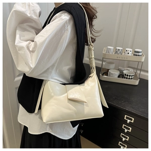 Hobo style cream shoulder bag worn by model in a modern minimalist indoor setting