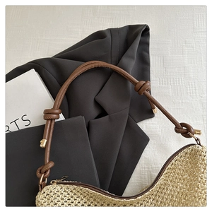Dettaglio della borsa hobo in paglia beige con trama intrecciata e tracolla annodata