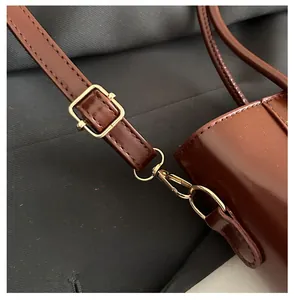 Detail of adjustable brown leather shoulder strap with gold-tone metal buckle and hardware