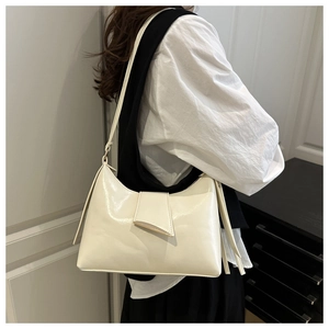 Side view of cream white PU leather shoulder bag on model in a minimalist setting