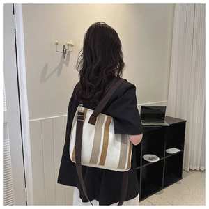 Detailed view of large striped canvas tote bag with brown adjustable shoulder strap