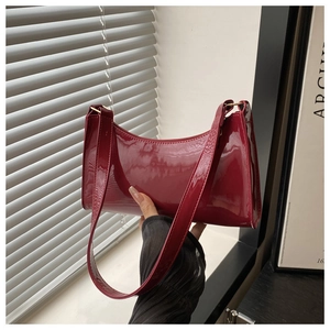 Bolso de hombro minimalista en charol rojo oscuro con acabado brillante y correa a juego
