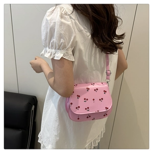 Detail of pink saddle bag with cherry prints and silver chain strap on model
