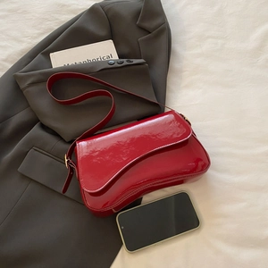 Chic red patent leather underarm bag with sleek shoulder strap on a neutral background