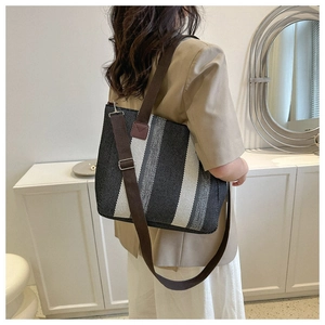 Striped woven tote bag shown on model with brown shoulder strap and large capacity