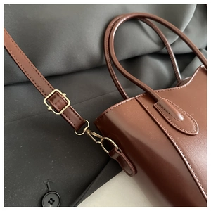 Detailed close-up of dark brown bucket bag with adjustable gold-tone strap buckle
