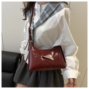Detail view of burgundy patent leather shoulder bag with elegant gold metal buckle hardware