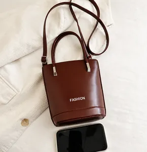 Detailed view of dark brown bucket bag showing polished leather texture and fashion logo