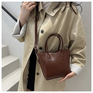 Detail showing the brown faux leather texture and FASHION embossed logo on bucket bag
