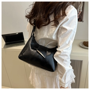 Detail of a black crescent shoulder bag with silver hardware and glossy leather finish