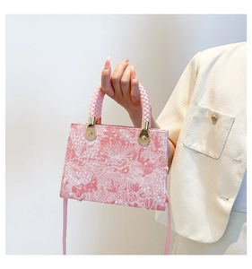 Detail der rosa Jacquard-Handtasche mit Blumenmuster, Webgriffen und Goldbeschlägen
