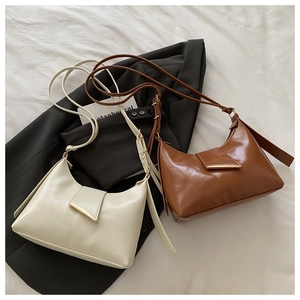 Detailed view of chic off-white and brown hobo bags with sleek gold buckles on a suit jacket