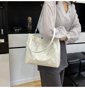 Detail der weißen Schmetterlingsstickerei und der Stoffstruktur dieser Shopper-Tasche