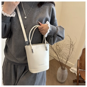 Détail d'un sac seau blanc avec finition lisse brillante et boucles en métal argenté