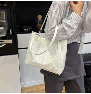 Detail der eleganten Schmetterlingsstickerei und 3D-Applikation auf elfenbeinfarbener Tasche