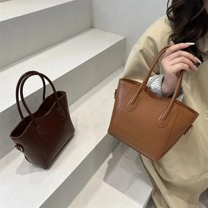 Chic minimalist leather bucket bag with top handle and FASHION embossed detail