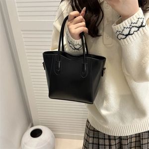 Minimalist black faux leather tote bag with embossed fashion text and slim handles