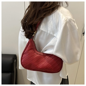 Close-up of red woven leather hobo bag with gold hardware worn by a model