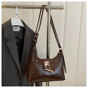Detail of dark brown glossy hobo bag with gold metal buckle and leather strap
