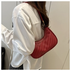 Detail of red woven hobo bag showing shoulder wear and side zipper construction