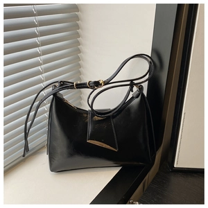 Close-up of a black hobo bag with a polished gold crescent moon buckle on a window sill