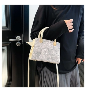 Detail einer Retro-Handtasche mit gewebten Griffen und goldenen Metallteilen am Modell