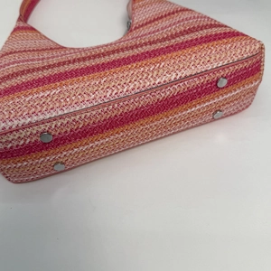 Detail of woven bucket bag featuring multicolor stripes and protective silver metal feet