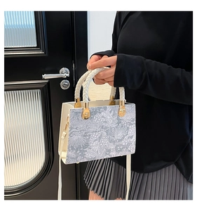Detailansicht der weißen Handtasche mit Blumenmuster, Webgriff und Goldringen