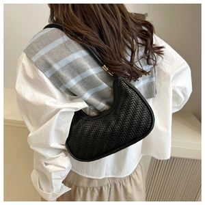 Detail of black woven crescent bag with leather strap and gold metal hardware