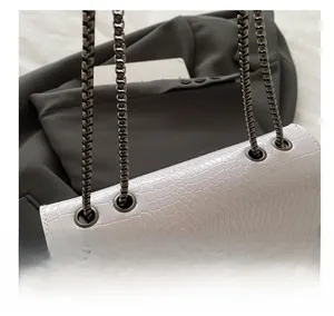 Detail of white crocodile embossed leather bag with pyramid stud and metal chain