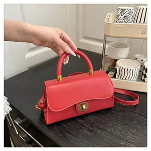 Details der roten quadratischen Handtasche mit Wellenklappe und Goldverschluss