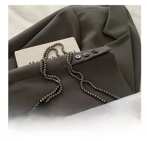 Detail of silver chain strap on light grey crocodile pattern faux leather handbag