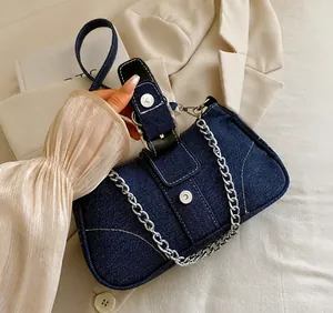 Détail du sac à bandoulière en denim bleu foncé avec chaîne argentée et boucle magnétique