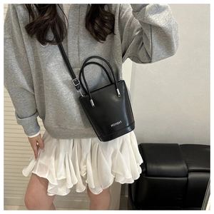 Détail d'un mini sac seau noir avec lettrage fashion et bandoulière réglable pratique