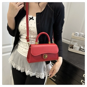Nahaufnahme einer roten Retro-Handtasche mit rundem goldfarbenem Drehverschluss und Klappe
