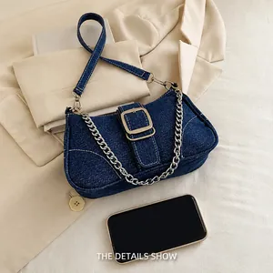 Détail du sac à bandoulière en denim avec chaîne argentée et téléphone pour taille