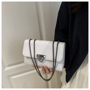 Detail of white crocodile pattern shoulder bag with a metallic chain strap and metal buckle