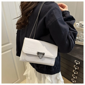 Detail view of a white crocodile texture crossbody bag with gold chain and metal buckle