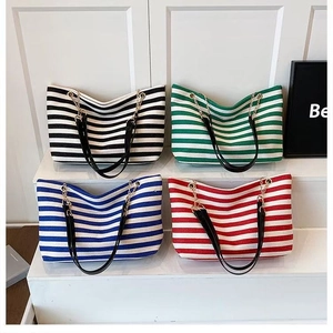 Detail of four colorful striped canvas tote bags with leather and metal chain straps