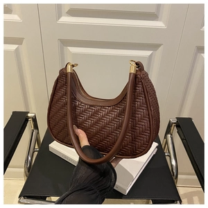 Detail of dark brown woven leather texture on a crescent shoulder bag with gold rings